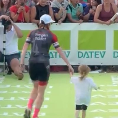 Natalie walking to the Challenge Roth finish with a child, in Team Oxygenaddict kit